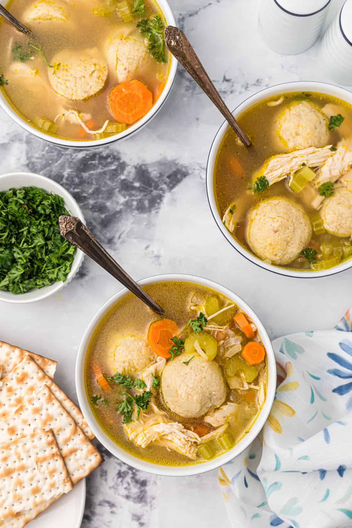 Zuppa Sostanziosa di Palle di Matzo 2 Tre ciotole di zuppa di matzo sono posizionate su un piano di lavoro in marmo.