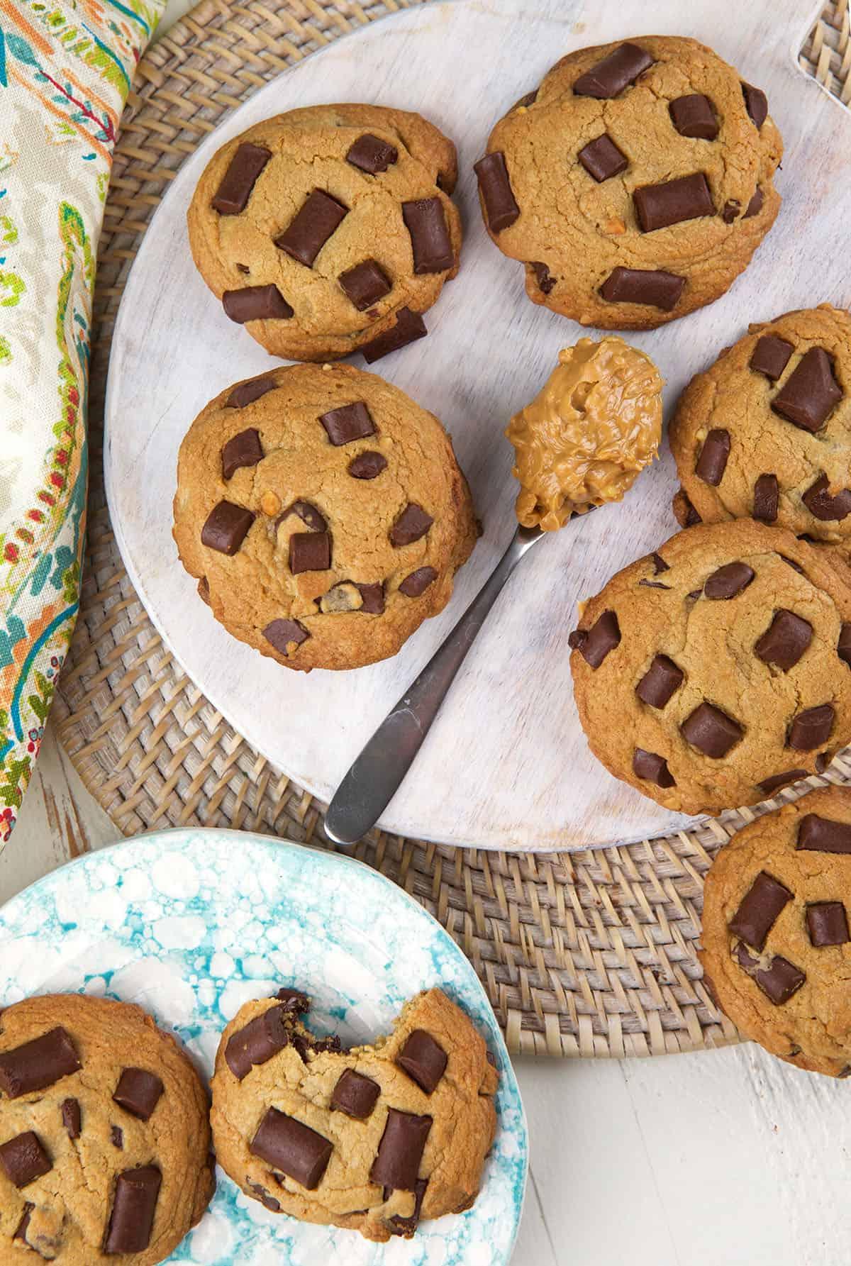 Biscotti alle Gocce di Cioccolato e Burro di Arachidi 2 Un cucchiaio con burro d'arachidi è posizionato accanto a una teglia di biscotti al burro d'arachidi e gocce di cioccolato.