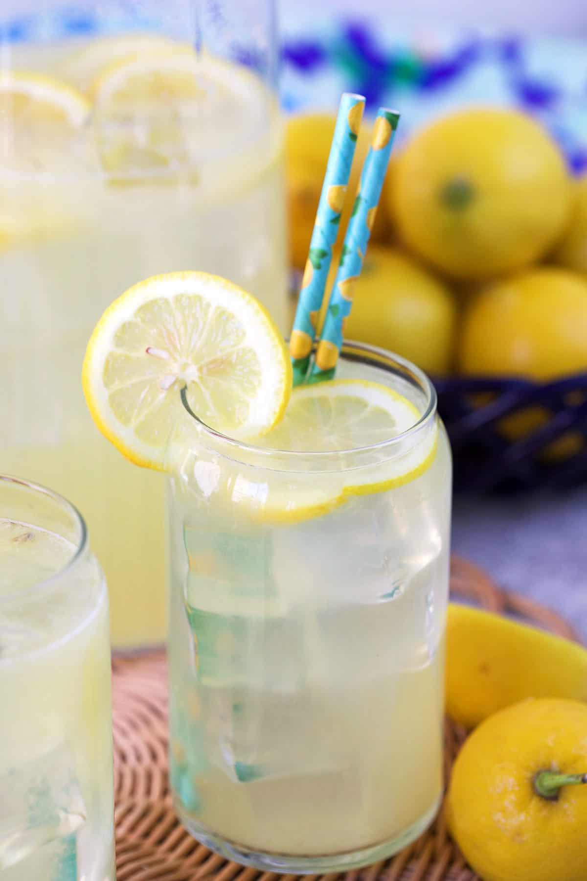 Ricetta della Limonata Fatta in Casa 2 Bicchiere di limonata con una fetta di limone e cannucce blu.