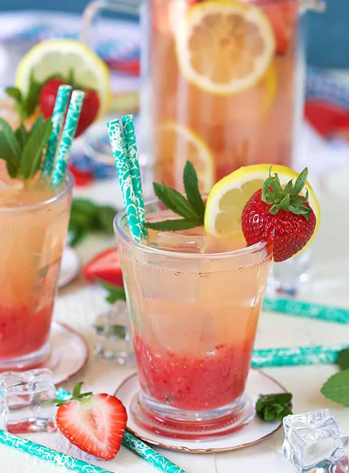 Limonata alle Fragole Fatta in Casa 2 Limonata alla fragola in un bicchiere decorato con fragola e limone, con una cannuccia di carta color turchese.