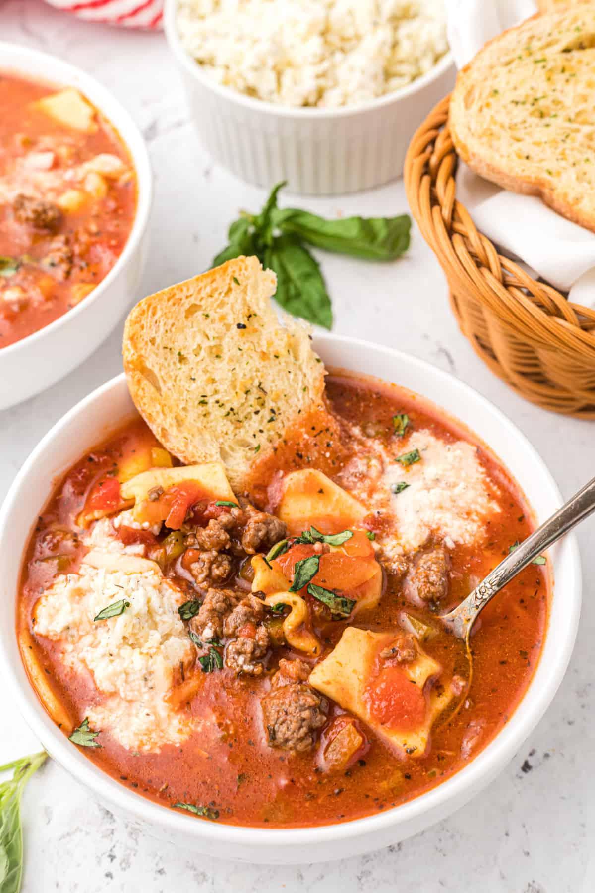 Zuppa di Lasagna Veloce e Facile 2 Una ciotola piena di zuppa di lasagna è posizionata su un piano di lavoro bianco.