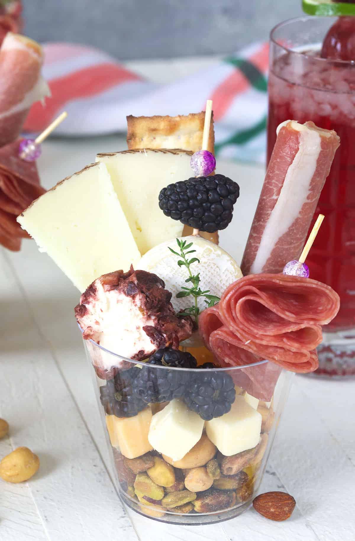 Facili Coppette di Salumi 2 Un bicchiere di plastica trasparente è riempito con ingredienti per charcuterie.