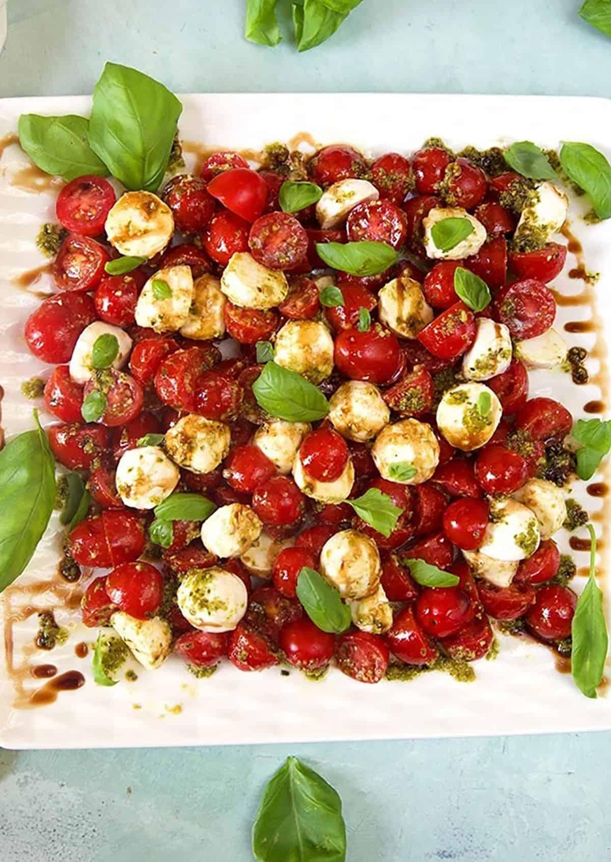 Insalata di Pomodoro e Mozzarella 2 Insalata Caprese vista dall'alto su un piatto bianco, ricca di pomodori, mozzarella e basilico fresco.