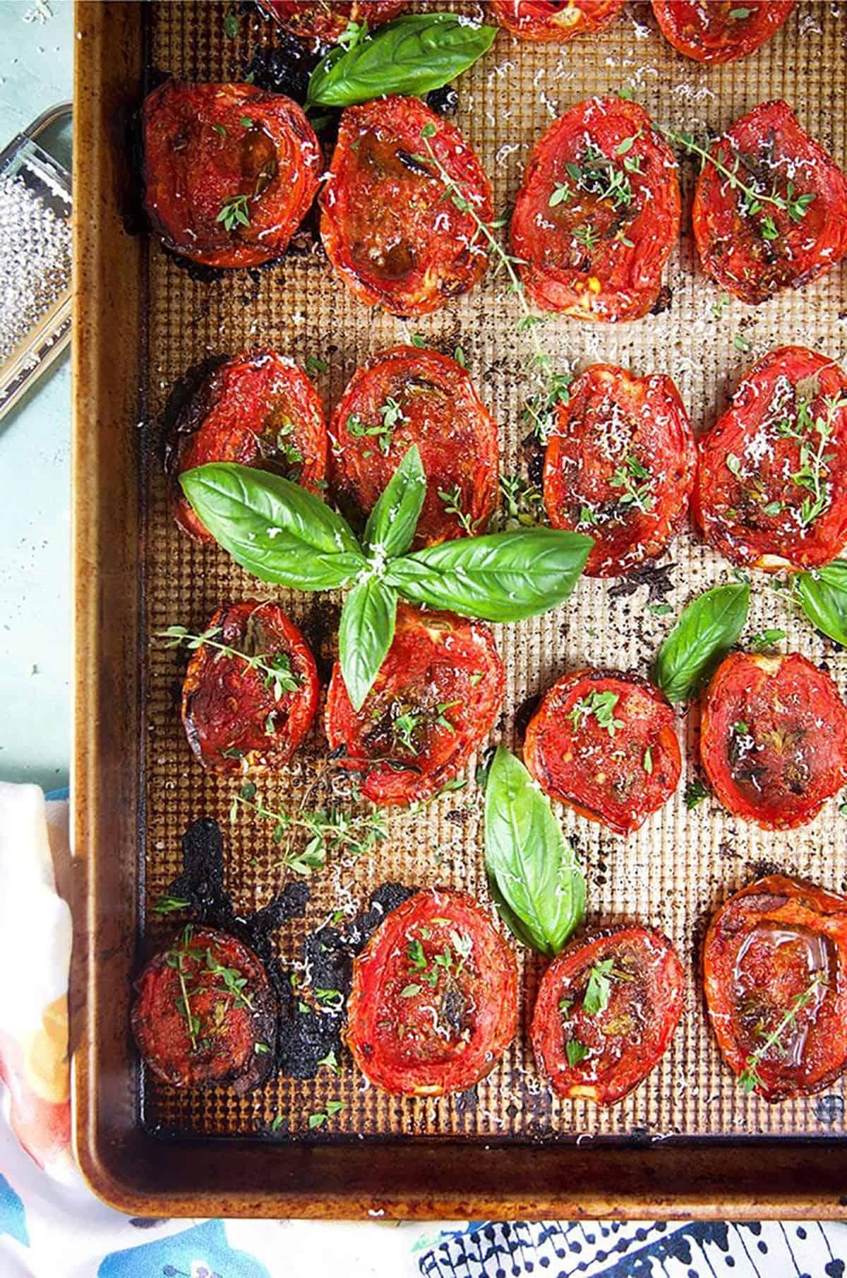 **Pomodori Arrostiti al Forno Facili** 2 Teglia di pomodori arrostiti al forno con basilico ed erbe aromatiche visti dall'alto.
