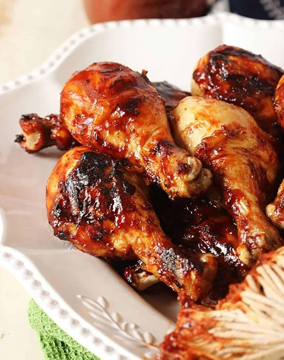 Cosce di Pollo al Barbecue 2 Cosce di pollo alla griglia su un piatto bianco.