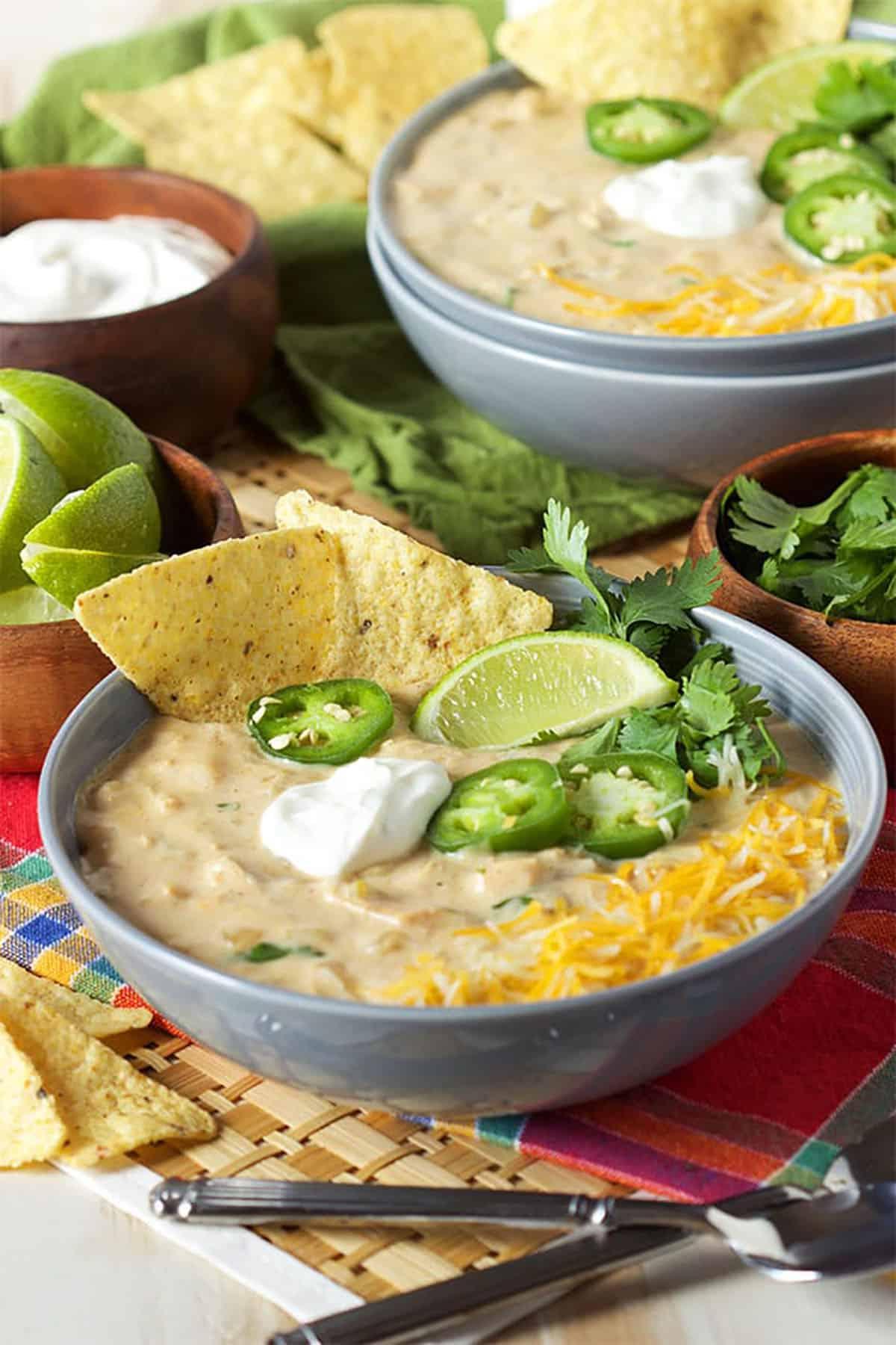 Il Miglior Chili Bianco Cremoso di Pollo 2 Ciotola di chili bianco di pollo guarnito con fette di jalapeño, uno spicchio di lime, formaggio grattugiato e panna acida.