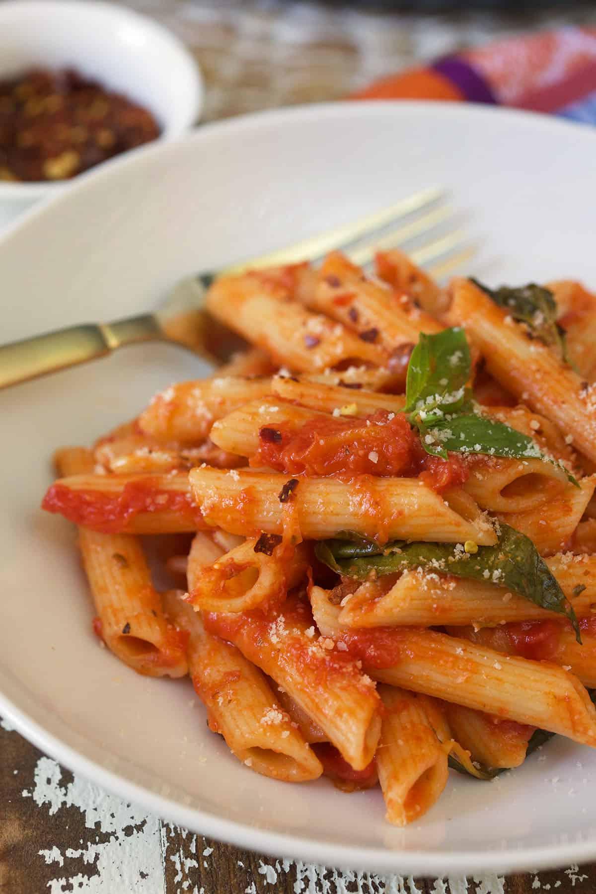 Penne al Pomodoro Veloce e Semplice 2 Un piatto di penne al pomodoro su un piatto bianco con una forchetta.