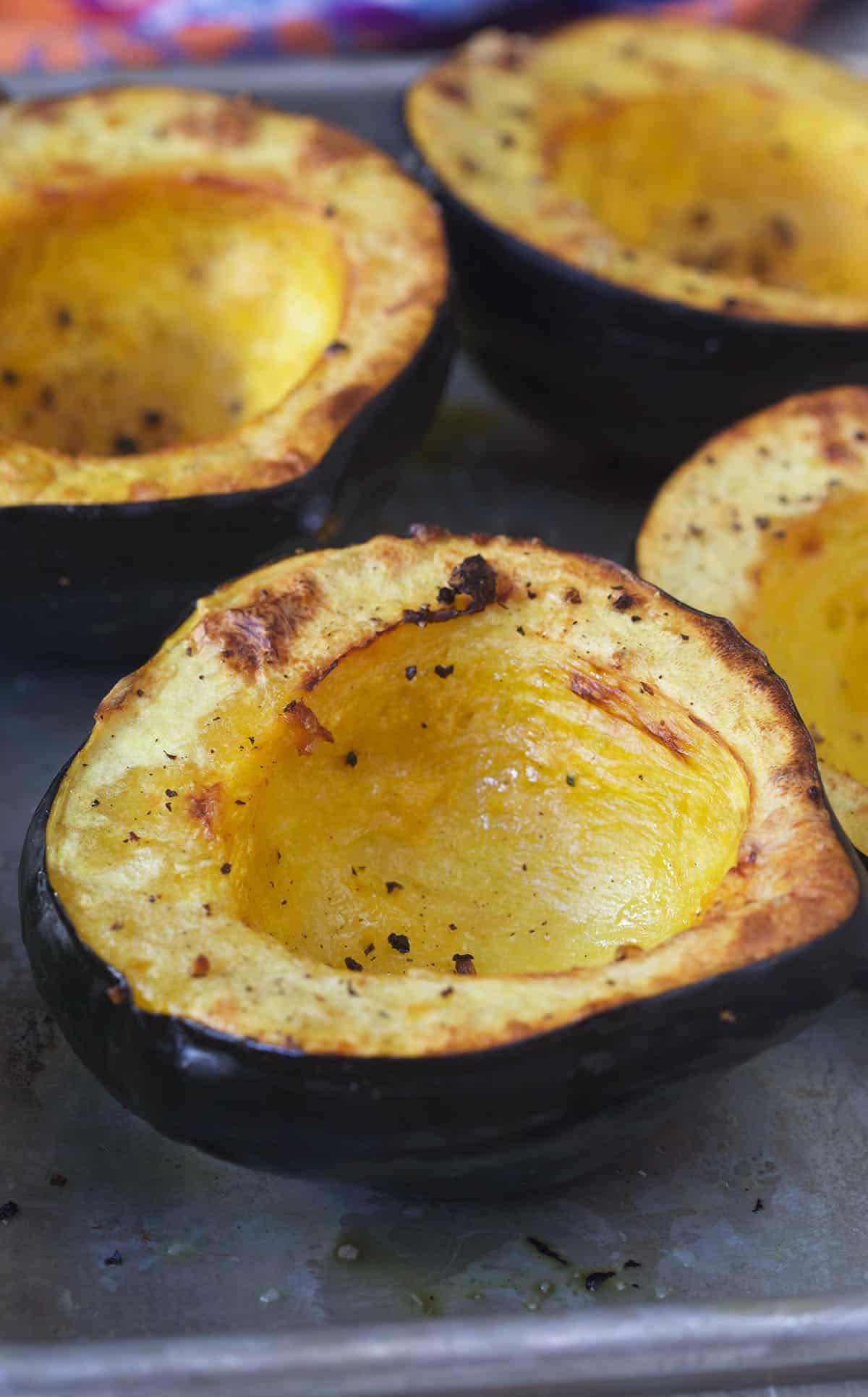 Come cucinare la Zucca Ghianda 2 Delle zucche acorn tagliate a metà sono posizionate su una teglia da forno.
