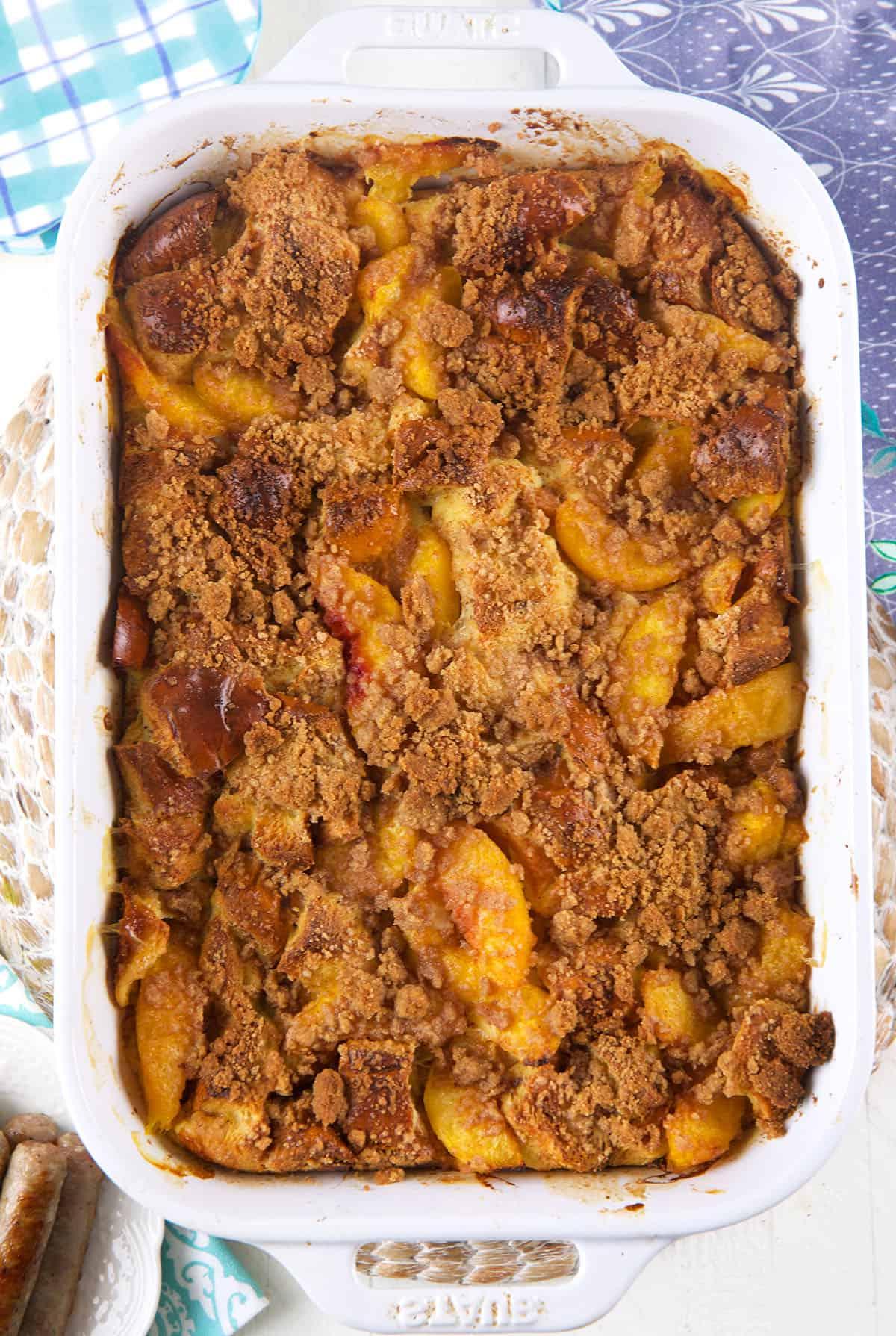 **Sformato di French Toast alle Pesche** 2 Una grande pirofila bianca è piena di toast francese alle pesche e crumble.