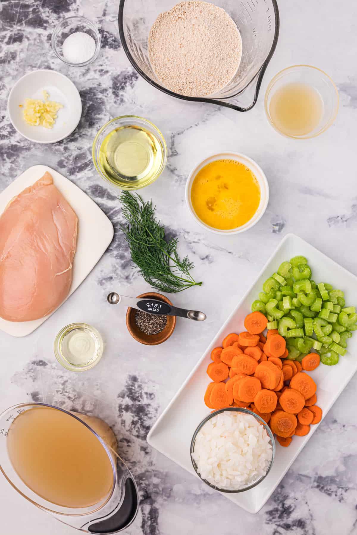 Zuppa Sostanziosa di Palle di Matzo 3 Gli ingredienti per la zuppa di matzo sono posizionati su un piano di lavoro in marmo.