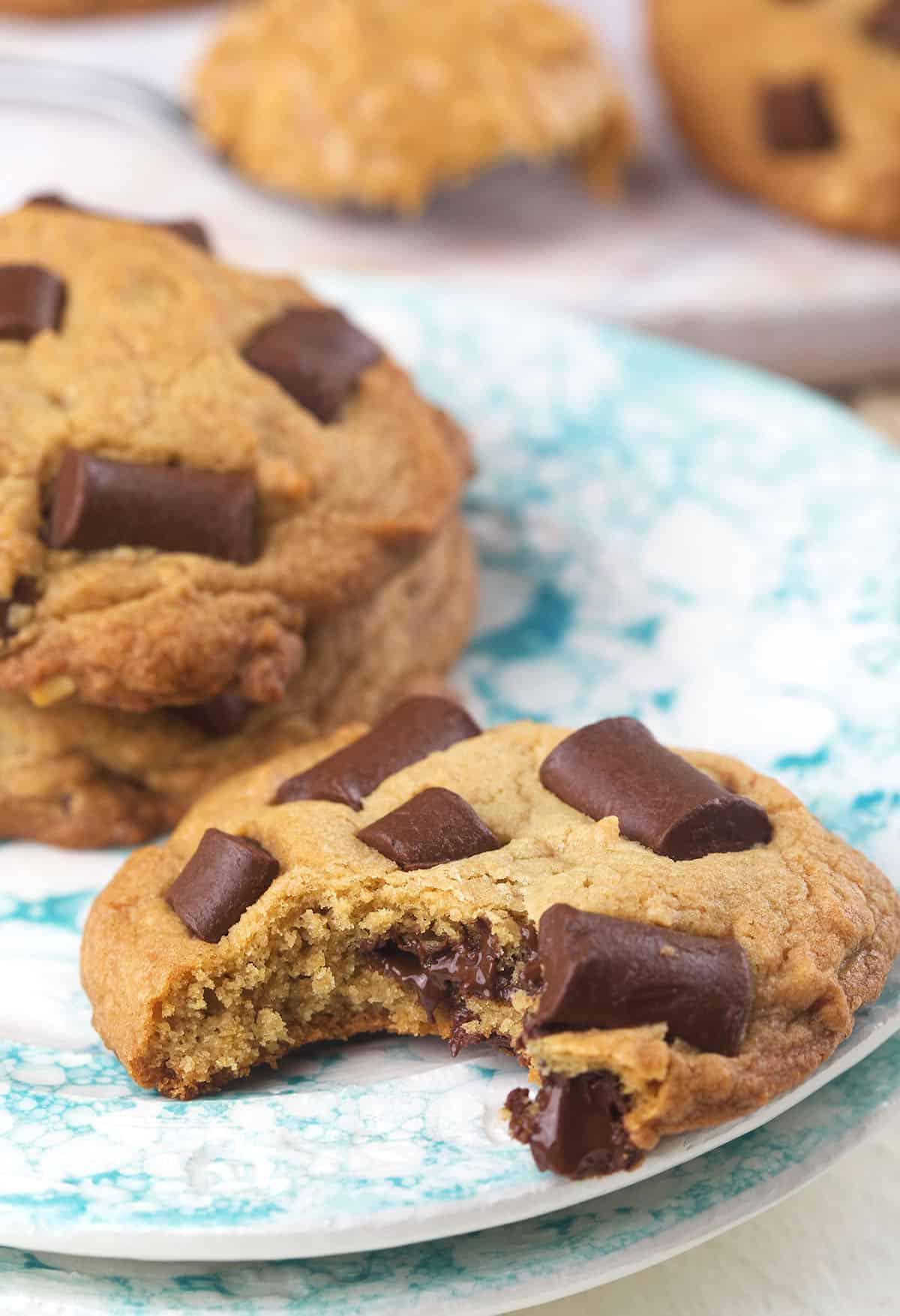 Biscotti alle Gocce di Cioccolato e Burro di Arachidi 3 Un biscotto morso è presentato su un piatto.