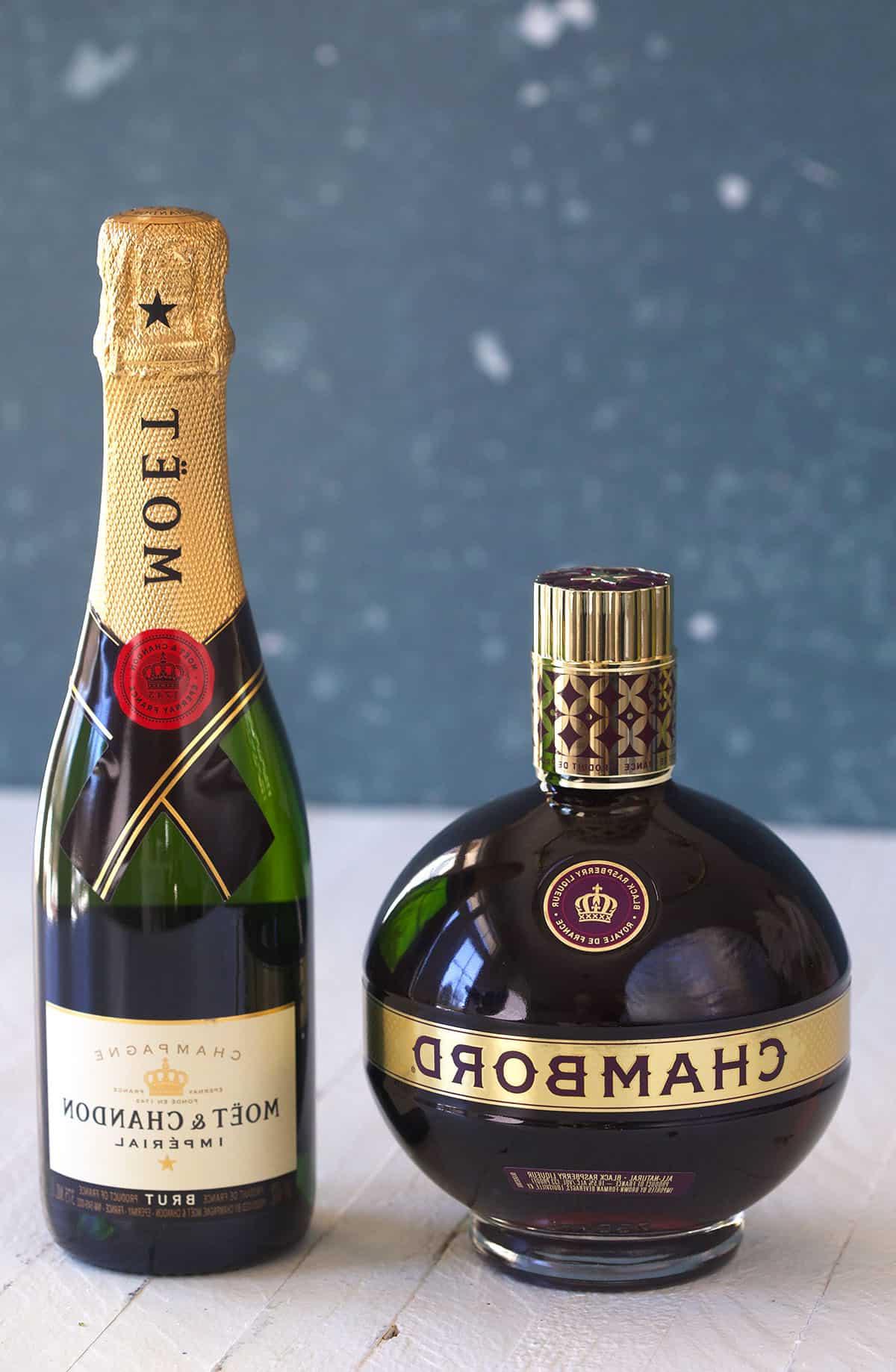 Classico Kir Royale 3 Gli ingredienti per il Kir Royale: Crème de Cassis e Champagne su una superficie bianca.