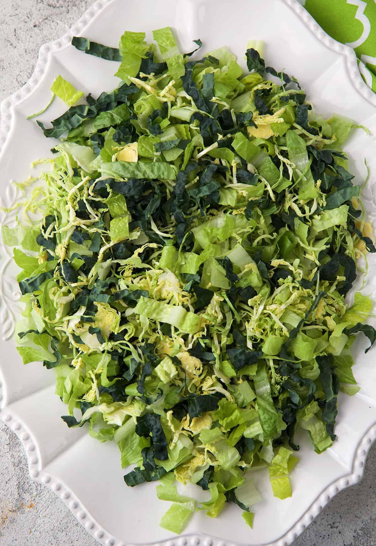 Insalata Caesar con Pollo 3 Un piatto bianco è sormontato da verdure fresche.