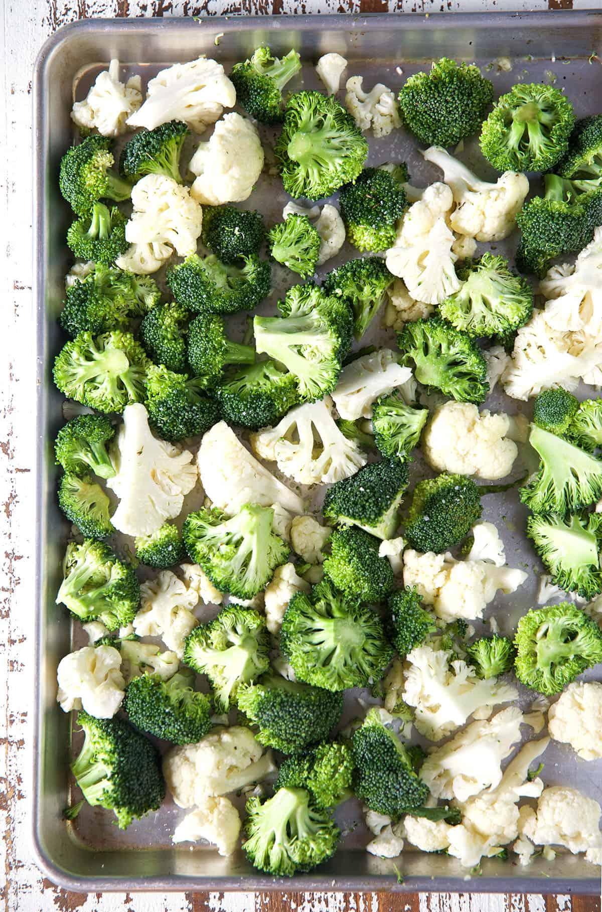 Facile Broccoli e Cavolfiore Arrostiti 3 Broccoli e cavolfiore crudi sono distribuiti su una teglia da forno.