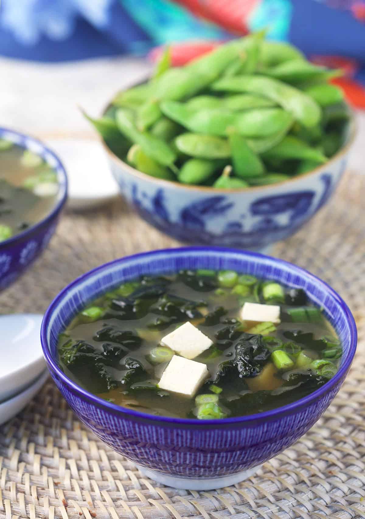 Zuppa di Miso Veloce e Facile 3 Una ciotola di edamame è posizionata accanto a una ciotola di zuppa di miso, pronta per essere gustata.