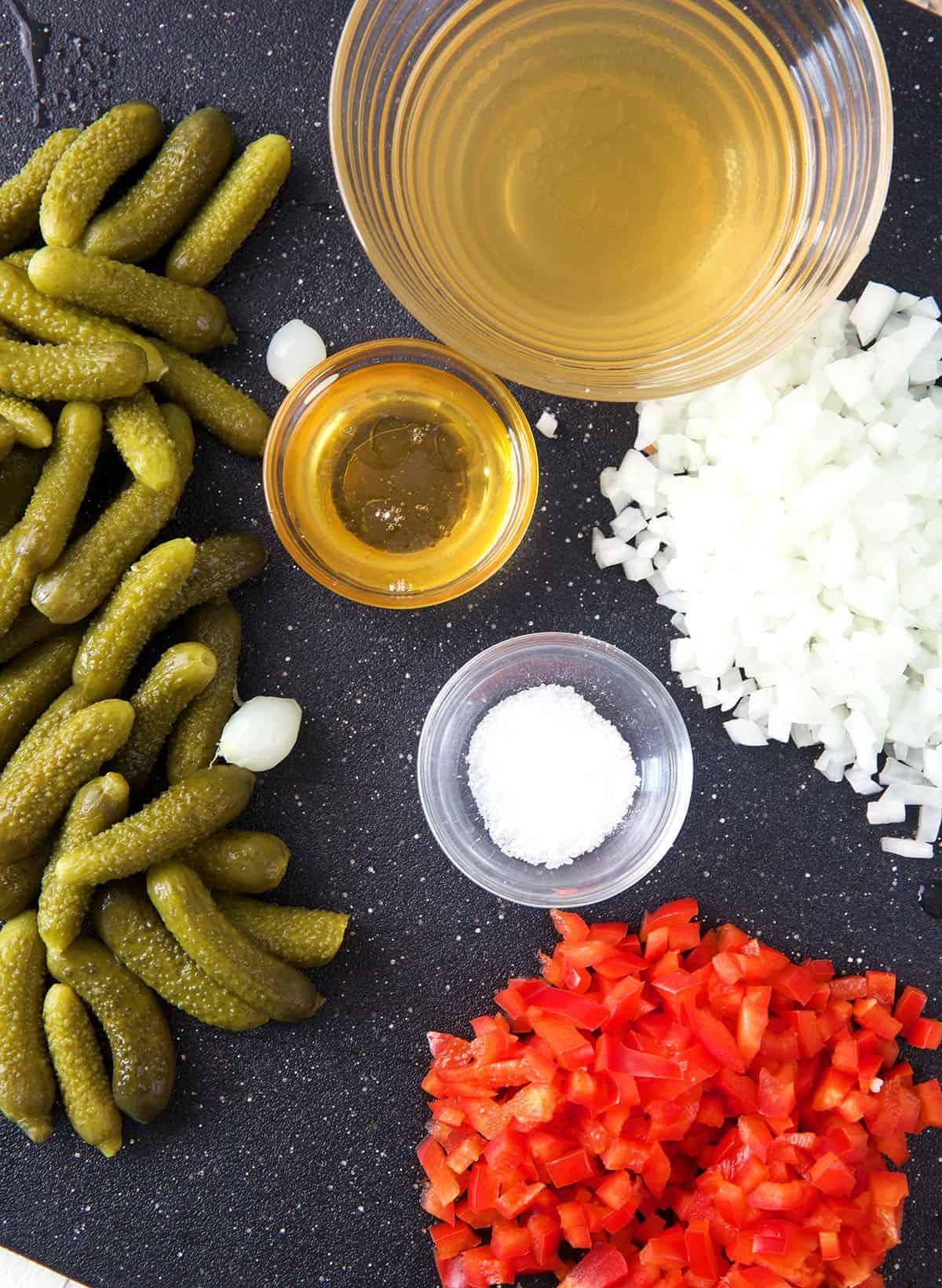 Salsa di Sottaceti Fatta in Casa 3 Gli ingredienti per la salsa di cetriolini sono disposti su una superficie scura.