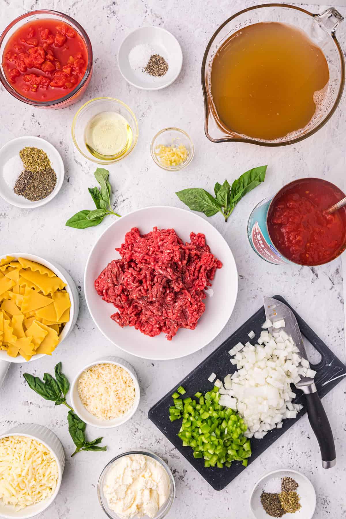 Zuppa di Lasagna Veloce e Facile 3 Gli ingredienti per la zuppa di lasagna sono disposti su un piano di lavoro bianco.