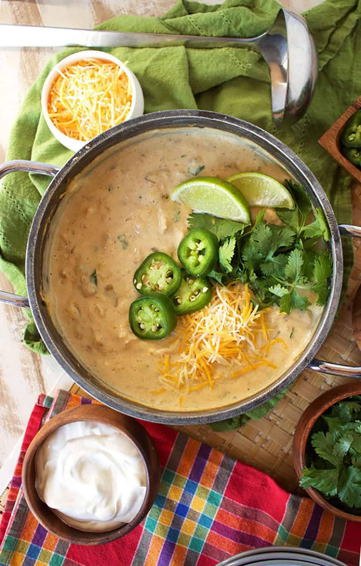 Il Miglior Chili Bianco Cremoso di Pollo 3 Pentola di chili bianco di pollo con fette di jalapeño, coriandolo, formaggio e due spicchi di lime.