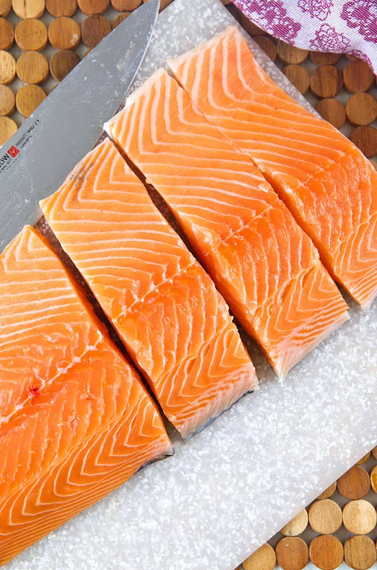 Salmone Glassato al Miso 3 Un filetto intero di salmone è tagliato in più pezzi pronti per la cottura.