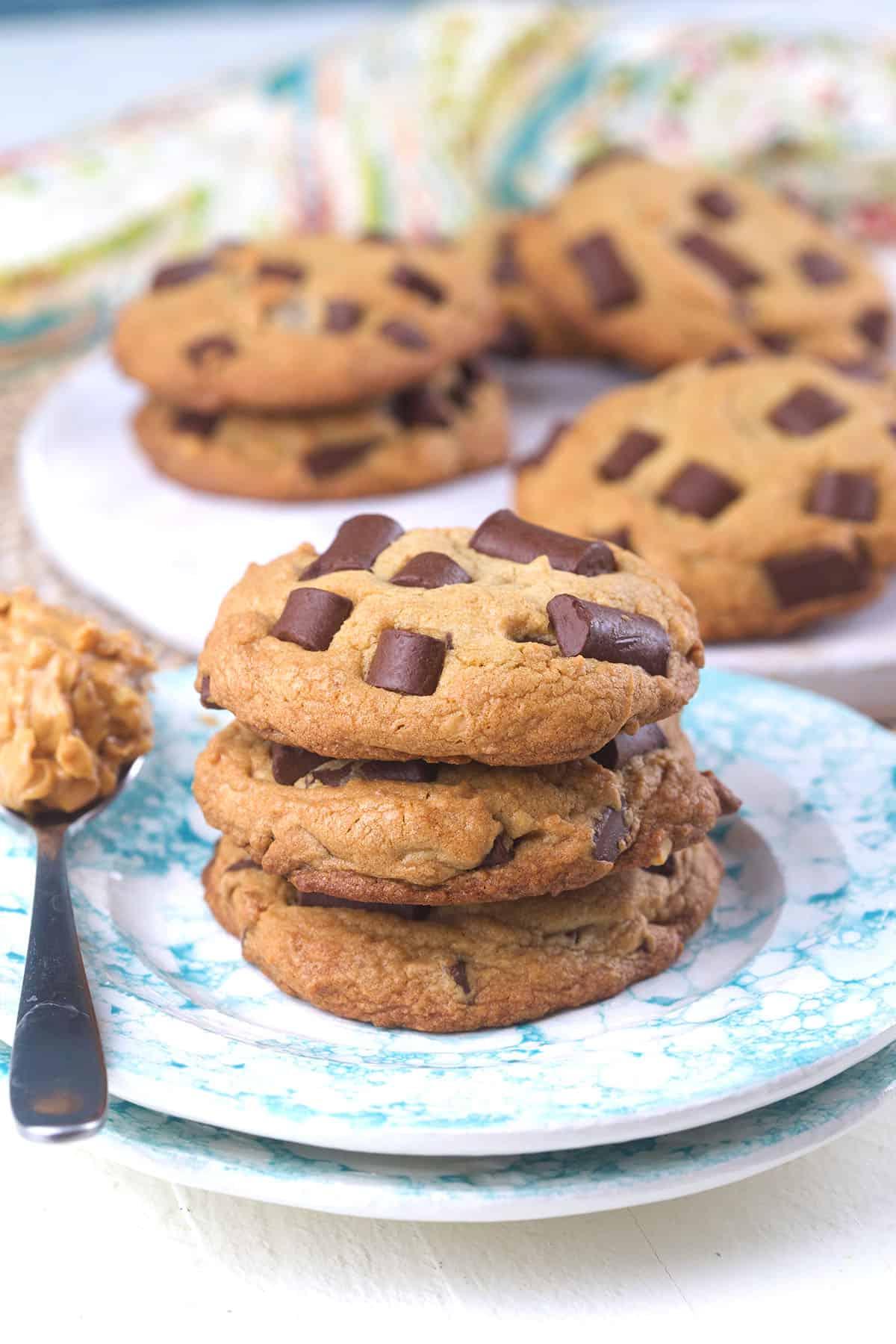 Biscotti alle Gocce di Cioccolato e Burro di Arachidi 4 I biscotti sono impilati in un piccolo mucchio su un piatto rotondo.