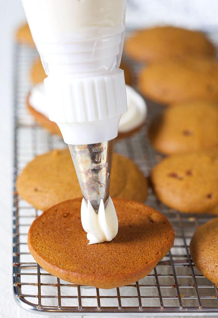 **Whoopie Pies alla Zucca con Ripieno al Mascarpone d'Acero** 4 Crema che viene spruzzata su un morbido biscotto alla zucca.