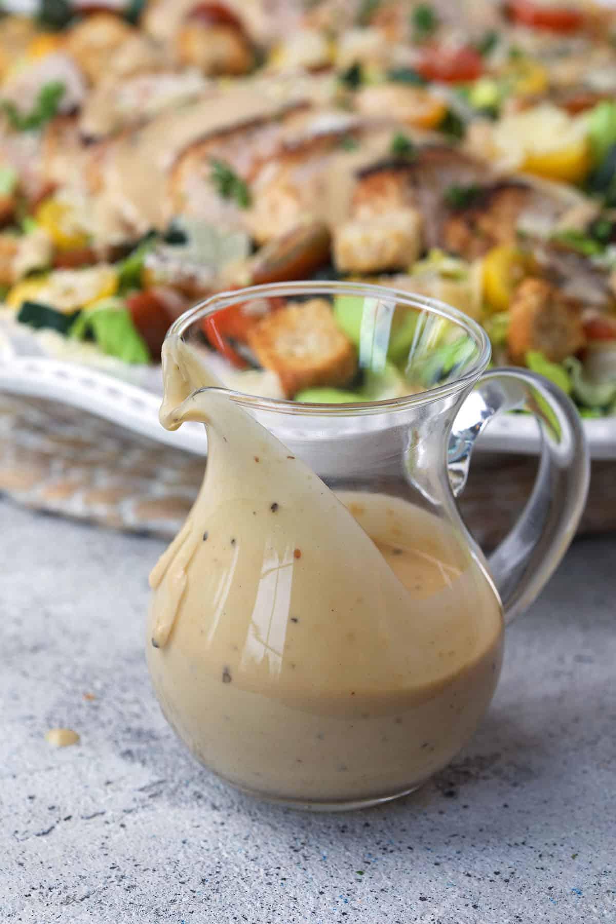Insalata Caesar con Pollo 4 Una piccola brocca di vetro è piena di condimento Caesar.