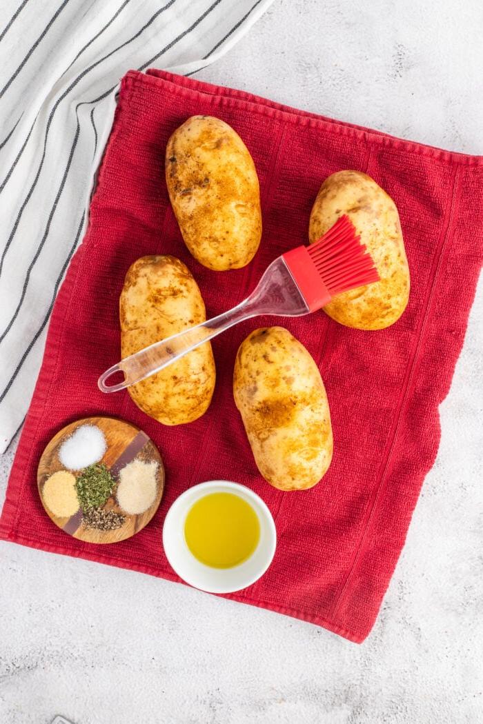 Patate al Forno Facili nella Friggitrice ad Aria 4 Una patata viene forata con una forchetta.