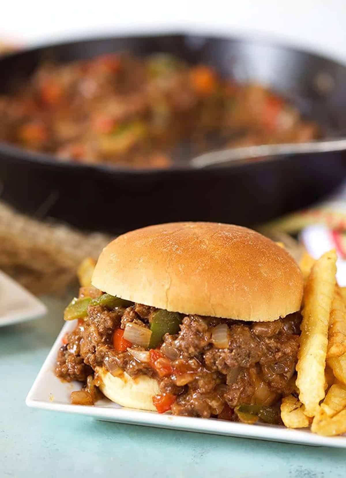 Sloppy Joe al Philly Cheesesteak 4 Philly cheesesteak sloppy joe su un piatto bianco con una padella sullo sfondo.