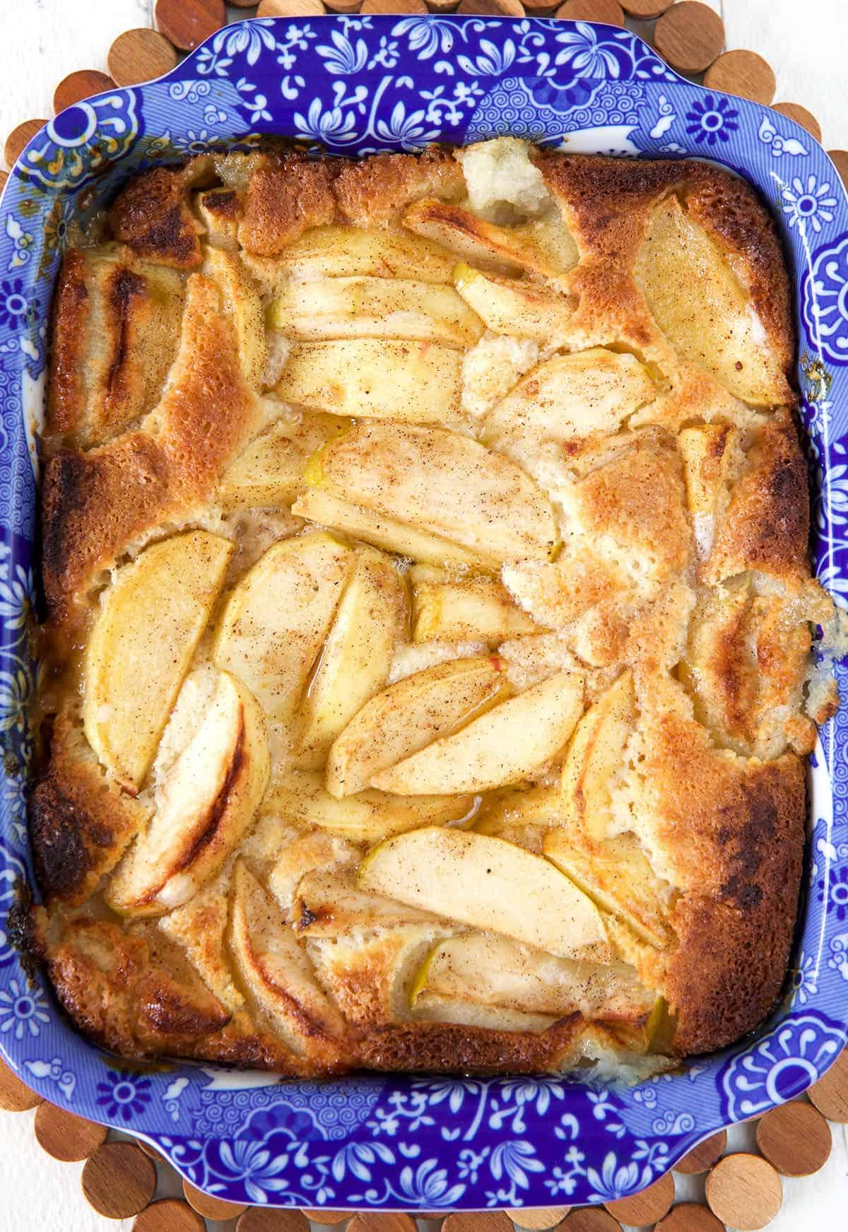 Un cobbler di mele appena sfornato, caldo e dorato, è presentato in una pirofila da forno blu.