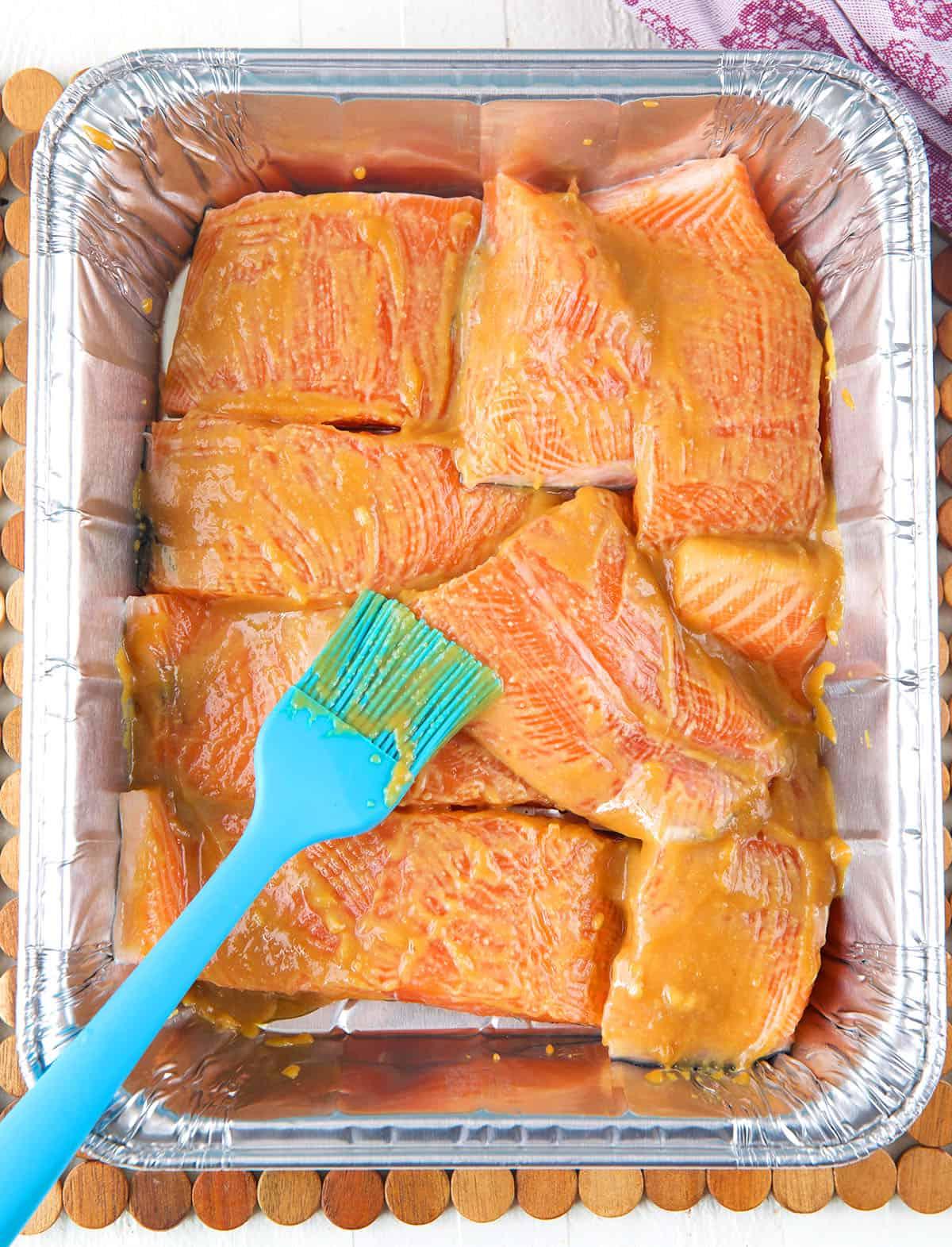 Salmone Glassato al Miso 4 Un pennello di gomma sta spalmando la glassa sul salmone.
