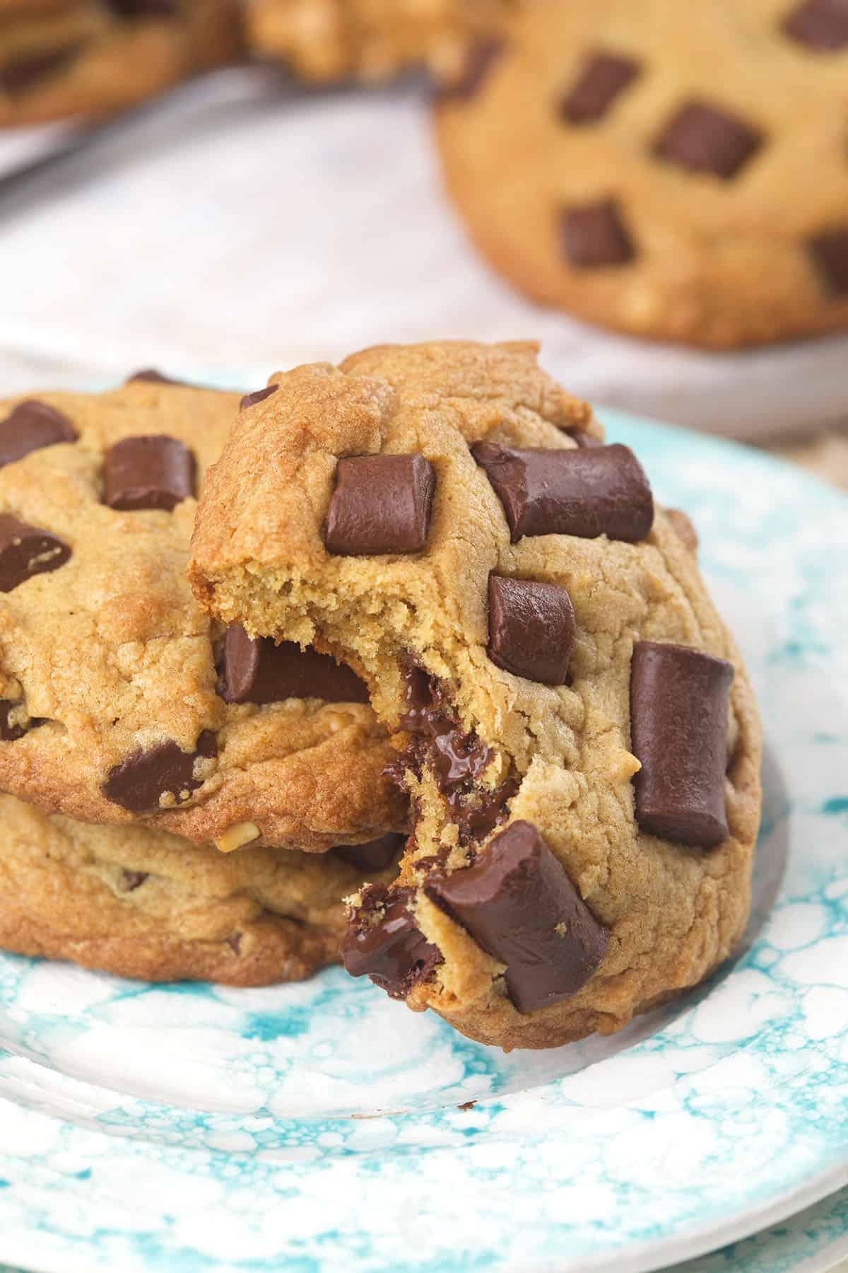 Biscotti alle Gocce di Cioccolato e Burro di Arachidi 5 Un biscotto morso è posizionato sopra un altro biscotto intero su un piatto.