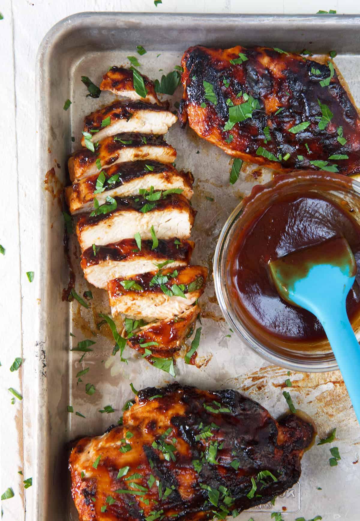 Petti di Pollo alla Griglia 5 Un petto di pollo è affettato e presentato accanto a una piccola ciotola di salsa BBQ extra.