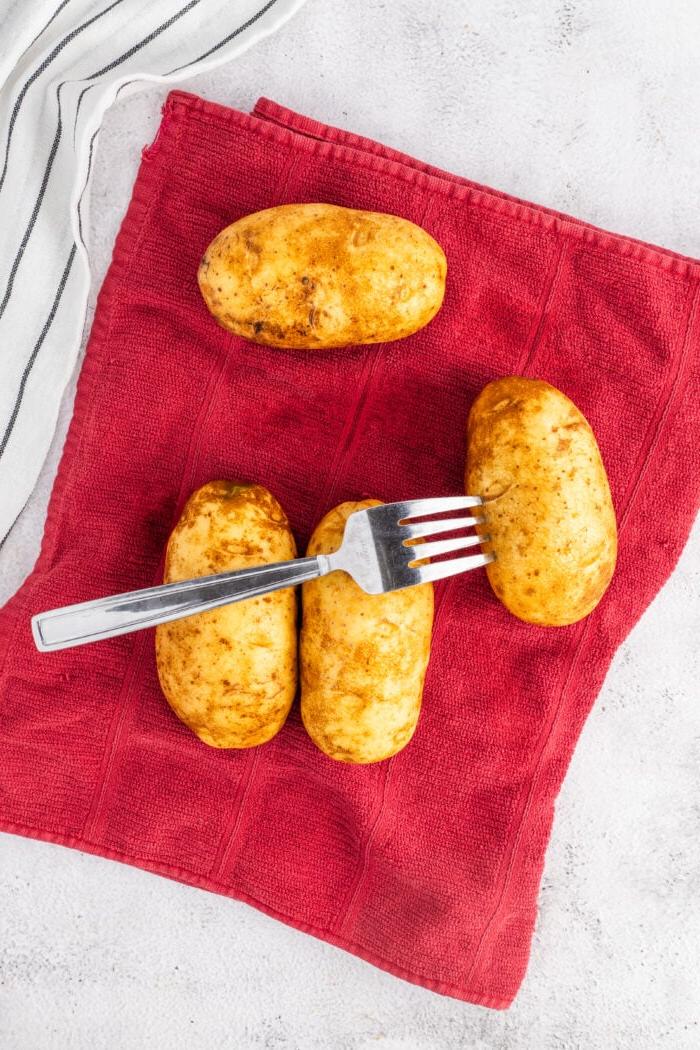 Patate al Forno Facili nella Friggitrice ad Aria 5 Una patata viene forata con una forchetta.