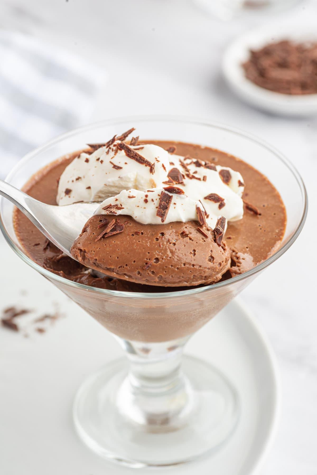 Pot de Crème al Cioccolato 5 Un cucchiaio affonda in un bicchiere di crema al cioccolato.