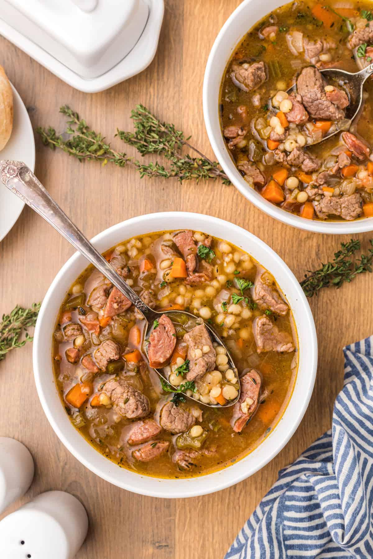 Zuppa di Manzo e Orzo con Salsiccia Andouille 5 Due ciotole bianche sono piene di zuppa.