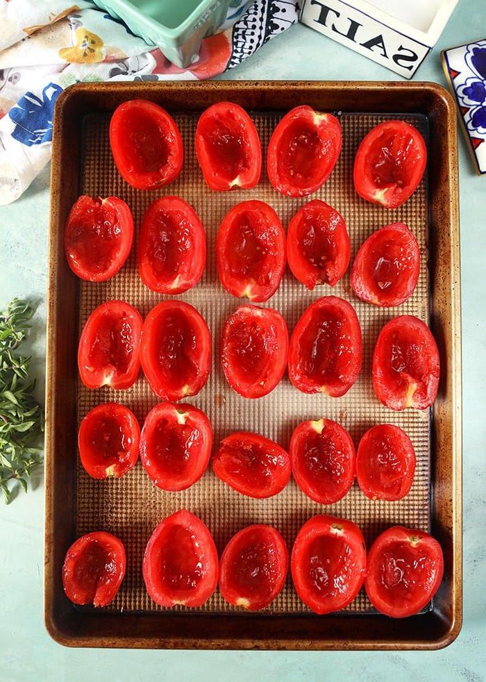 **Pomodori Arrostiti al Forno Facili** 5 Metà di pomodori prugna disposti in file ordinate su una teglia da forno, pronti per la cottura.
