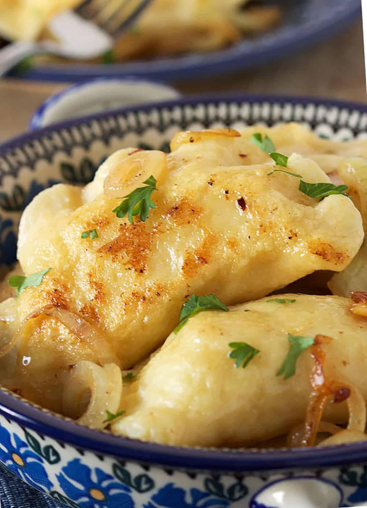 La migliore ricetta di pierogi di patate 5 Un pierogi di patate in una pirofila di ceramica polacca blu e bianca.