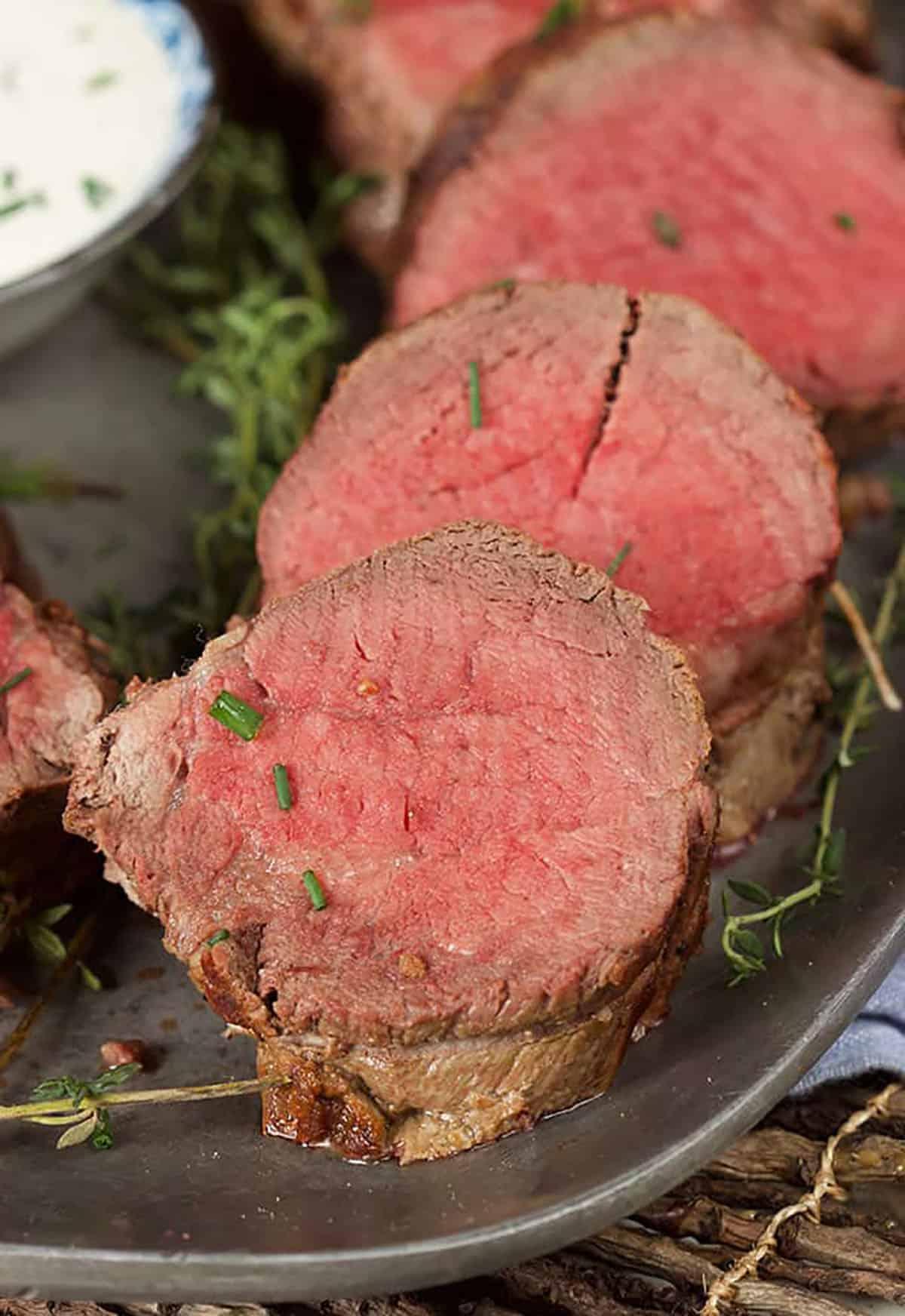 Arrosto Semplice di Filetto di Manzo 5 Tre fette di filetto di manzo su un piatto cosparse di erba cipollina tritata.