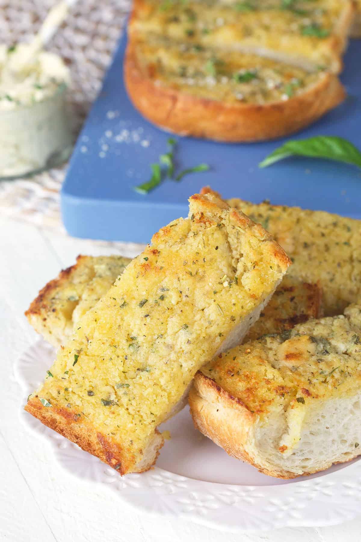 Pane all'aglio fatto in casa 5 Fette di pane all'aglio sono disposte su un piccolo piatto bianco.