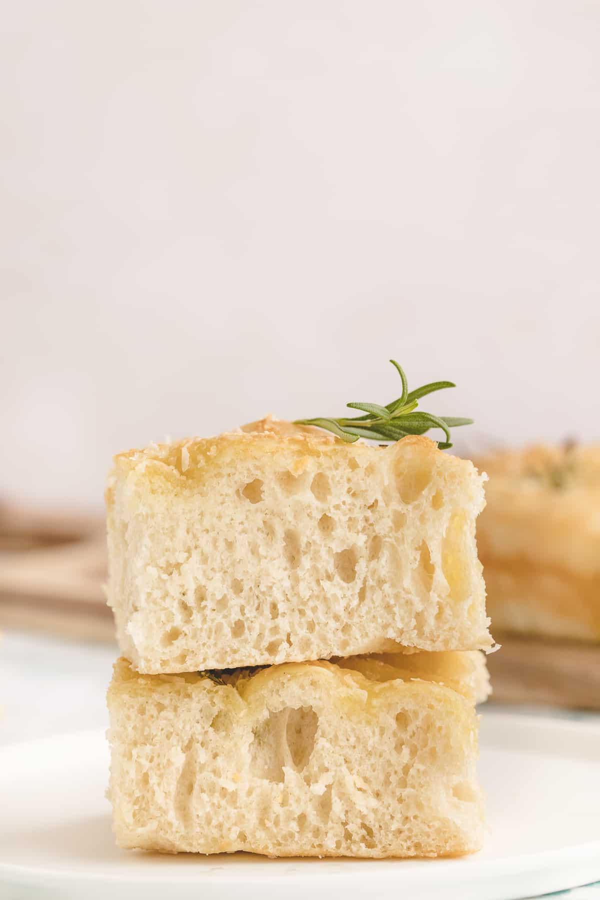 Focaccia all'Aglio e Rosmarino 5 Due pezzi di focaccia sono posizionati su una superficie bianca.