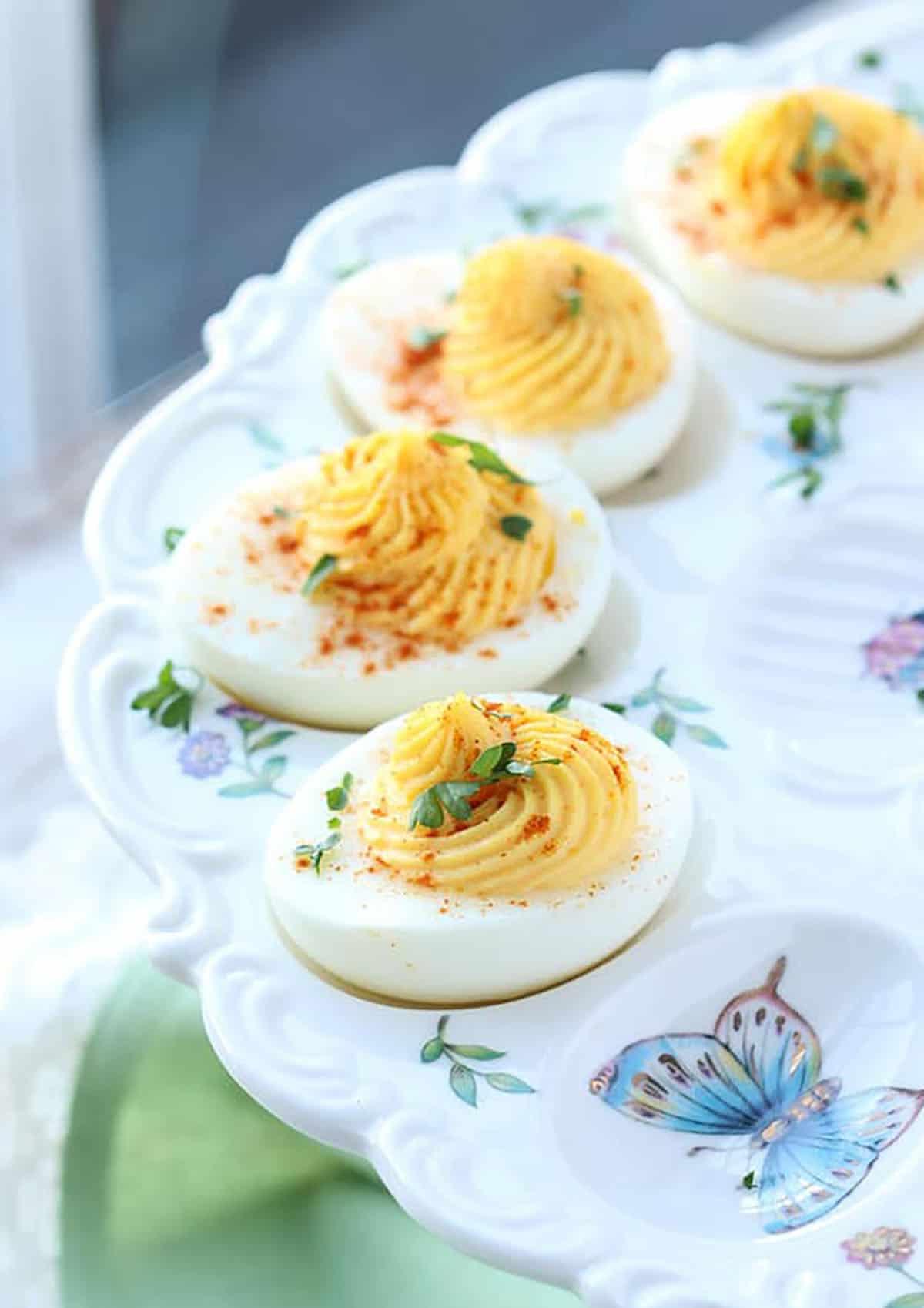 La migliore ricetta di uova ripiene di sempre 5 Quattro uova ripiene su un piatto decorativo per uova alla diavola
