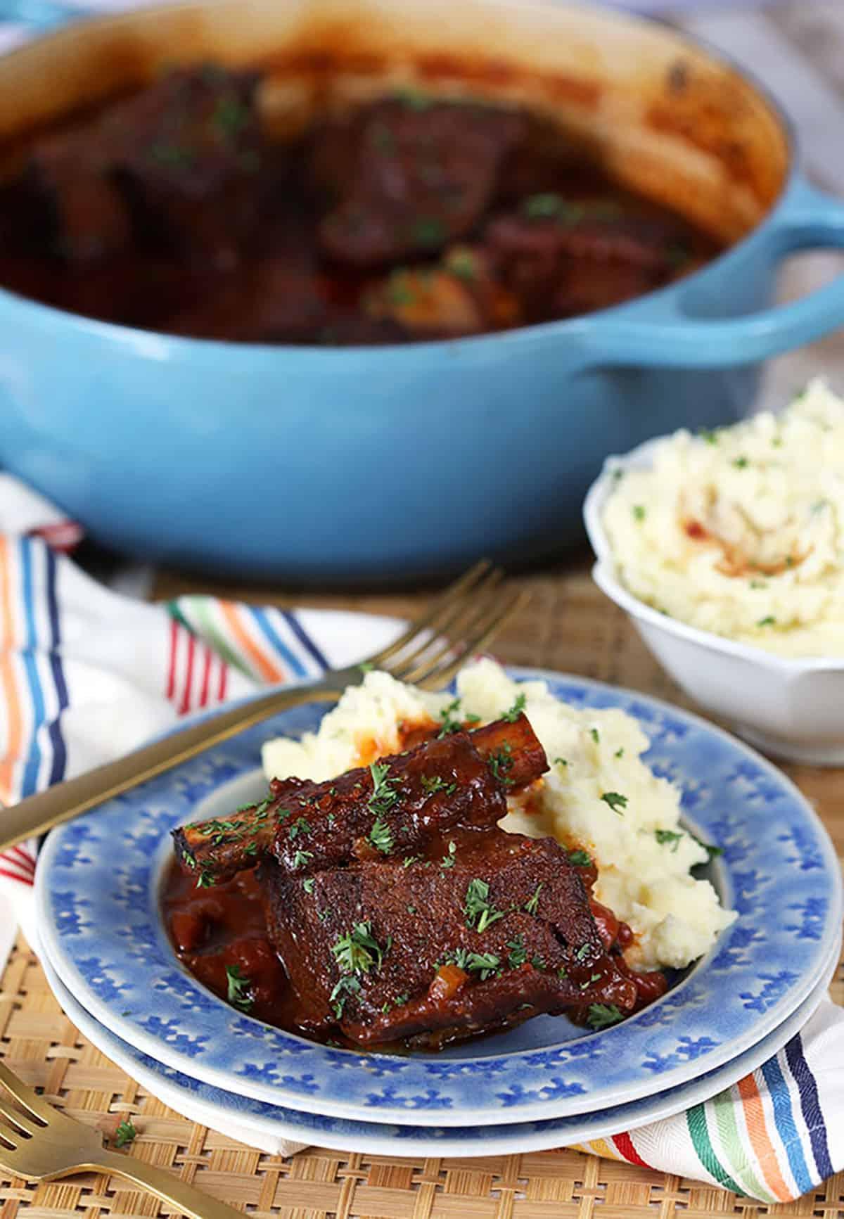 Brasato di Costine di Manzo al Miele e Chipotle 6 Costine Brasate su un piatto blu con purè di patate