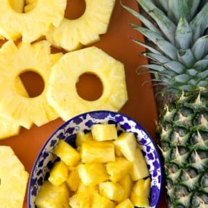 Come Tagliare un Ananas 6 Fette e cubetti di ananas sono posti accanto a un ananas intero.