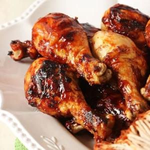 Cosce di Pollo al Barbecue 6 Cosce di pollo alla griglia su un piatto bianco.