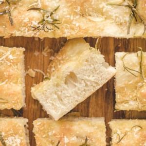 Focaccia all'Aglio e Rosmarino 6 Fette di focaccia sono posizionate su un tagliere di legno.