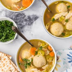 Zuppa Sostanziosa di Palle di Matzo 6 Tre ciotole di zuppa di matzo sono posizionate su un piano di lavoro in marmo.