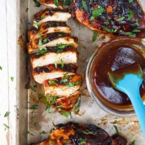 Petti di Pollo alla Griglia 6 Un petto di pollo affettato presentato accanto a una piccola ciotola di salsa BBQ extra.