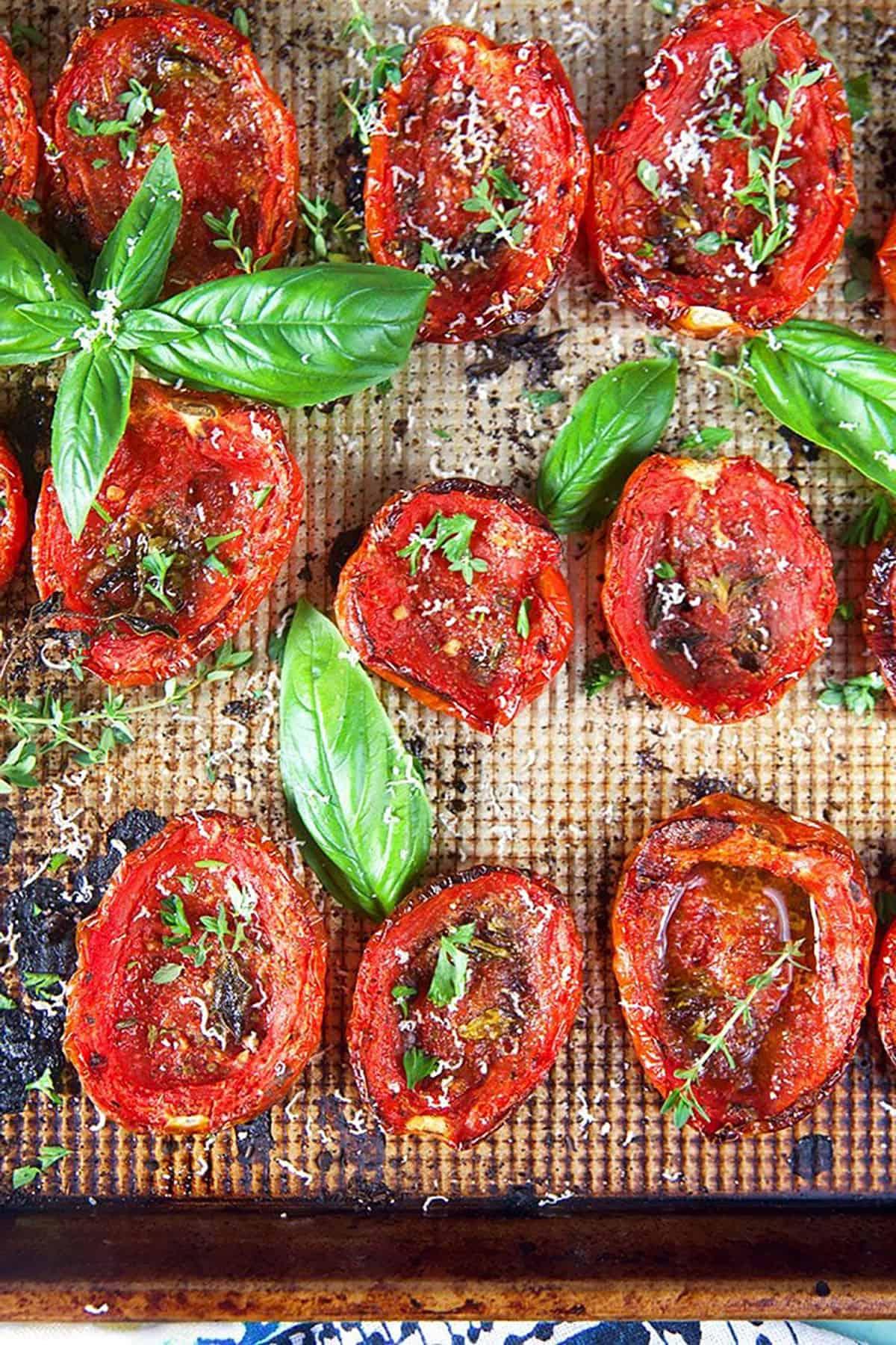 **Pomodori Arrostiti al Forno Facili** 7 Primo piano di pomodori arrostiti al forno con basilico ed erbe aromatiche, che mostrano la loro consistenza caramellata.