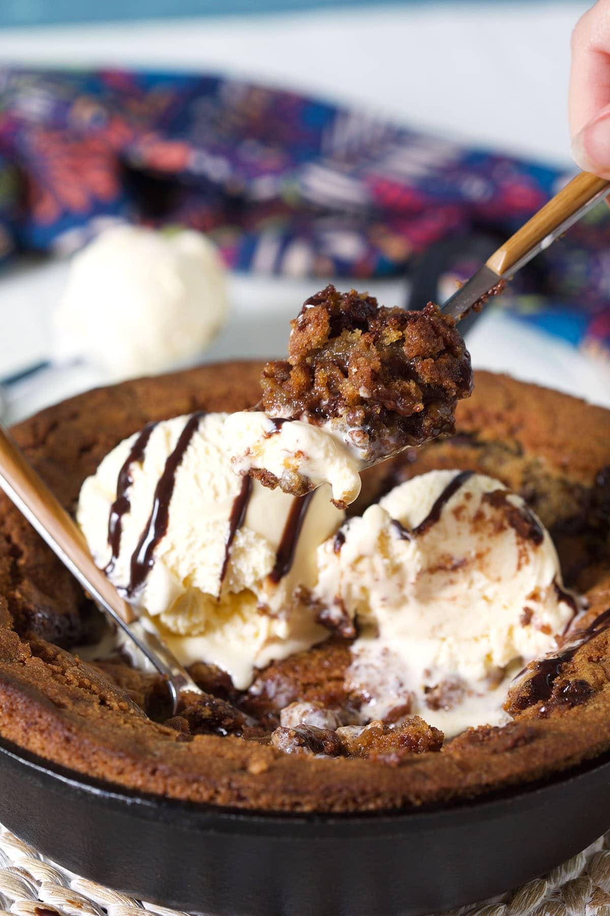Biscotto-Pizza Fatto in Casa con Gocce di Cioccolato 7 Un morso di pizookie viene sollevato dalla padella calda.