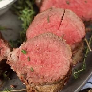 Arrosto Semplice di Filetto di Manzo 7 Tre fette di filetto di manzo su un piatto cosparse di erba cipollina tritata.